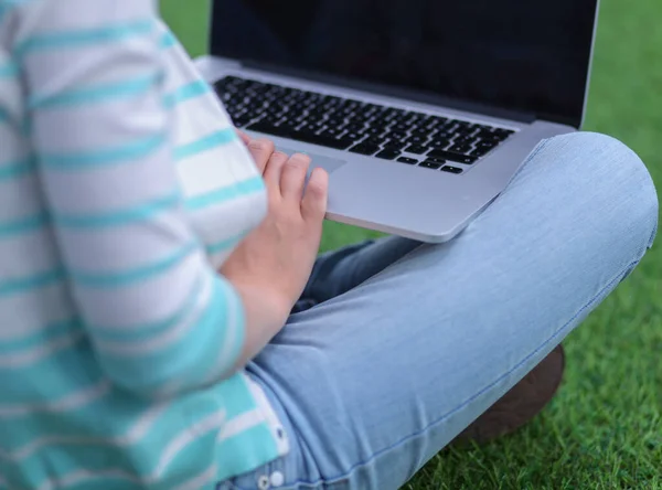 Ung kvinna med laptop sitter på grönt gräs. Porträtt ung kvinna — Stockfoto