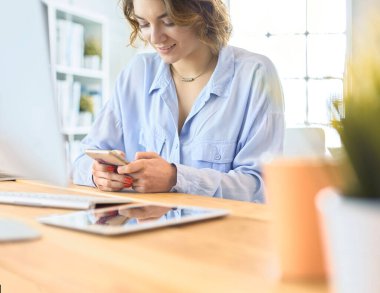 Genç iş kadını, ofiste dizüstü bilgisayarın önünde otururken mesaj atıyor.