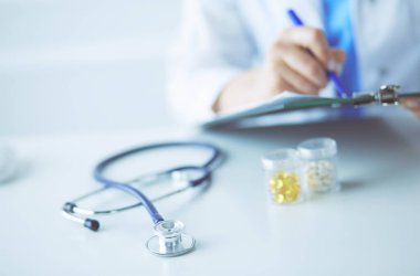 Kadınların elleri bir kağıt parçasına yazı yazıp masasında kalem bırakırlar.