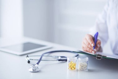 Steteskop cam masanın üzerinde duruyor. Yoğun bir doktor geçmişinde dizüstü bilgisayarı var. İlaç ya da eczane konsepti. Doktor çalışma masasında tıbbi aletler