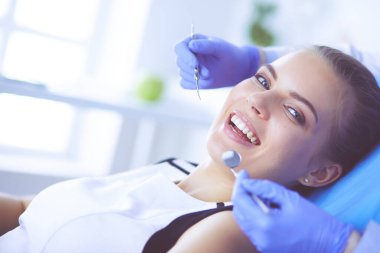 Dişçi muayenehanesinde diş muayenesi yapan ağzı açık genç bir kadın hasta..