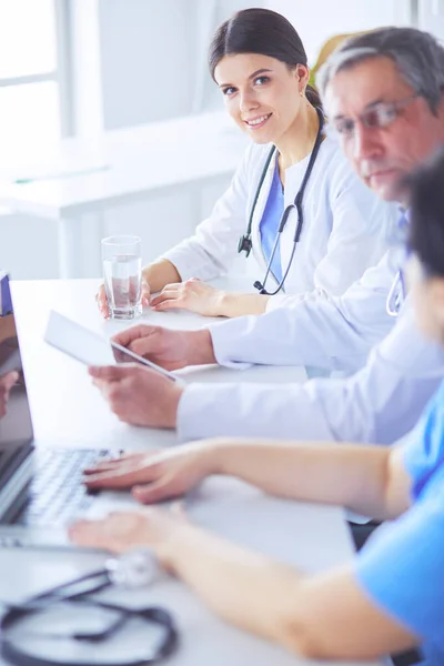Lachende arts met behulp van een laptop werken met haar collega 's in een heldere ziekenhuiskamer — Stockfoto