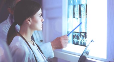 Bir grup doktor bir klinikte röntgenleri inceliyor, teşhis koymayı düşünüyorlar.