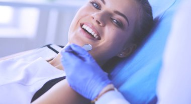 Güzel gülüşü olan genç bir bayan hasta dişçi muayenesi için dişçiye gidiyor..