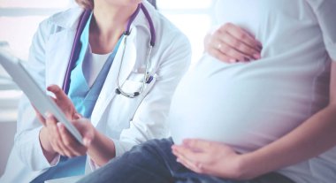 Gülümseyen kadın doktor resimlerini tablette hastanedeki hamile genç bayana gösteriyor..