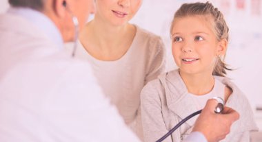 Steteskoplu kız ve doktor kalp atışlarını dinliyor.
