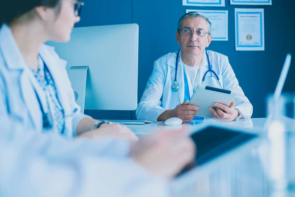 Equipe médica séria usando um laptop em um escritório brilhante — Fotografia de Stock