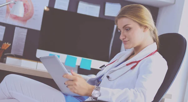 디지털 태블릿을 들고 책상에 앉아 있는 여의사 — 스톡 사진