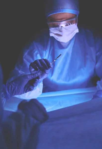 Médico realizando cirugía en un fondo oscuro. — Foto de Stock