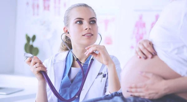 Jovem médica com estetoscópio falando com mulher grávida no hospital. — Fotografia de Stock