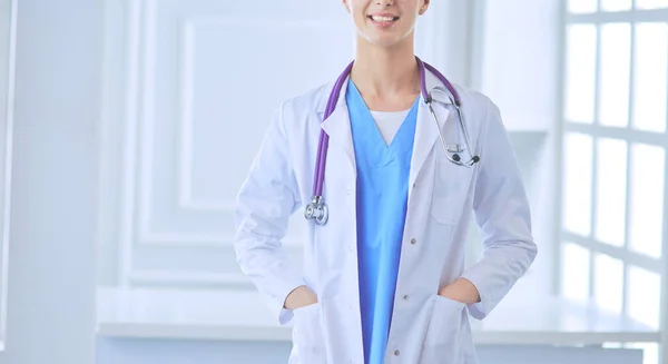 Young doctor woman standing near table, isolated on white background