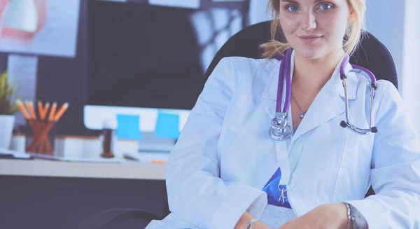 Beautiful young smiling female doctor sitting at the desk — Stock Photo, Image