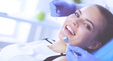 Dişçi muayenehanesinde diş muayenesi yapan ağzı açık genç bir kadın hasta..