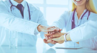 Doktorlar el ele tutuşup yakın çekim yapıyor.