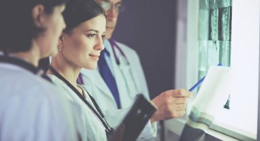 Bir grup doktor bir klinikte röntgenleri inceliyor, teşhis koymayı düşünüyorlar.