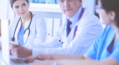 Parlak bir hastane odasında meslektaşlarıyla çalışan gülümseyen bir doktor.