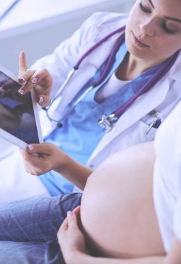Genç bayan doktor klinikte hamile kadını muayene ediyor..