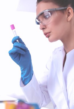 Kadın araştırmacı, beyaz arka planda izole edilmiş ilaç şişeleri ve mataralarla çevrili.