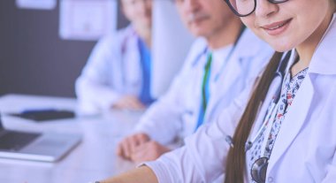 Ciddi bir tıbbi ekip parlak bir ofiste dizüstü bilgisayar kullanıyor.