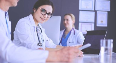 Ciddi bir tıbbi ekip parlak bir ofiste dizüstü bilgisayar kullanıyor.