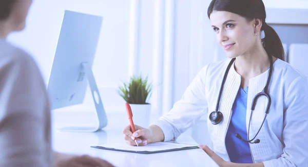 Médico y paciente discutiendo problemas médicos en una sala de consulta del hospital. Doc rellenando un formulario de pacientes — Foto de Stock