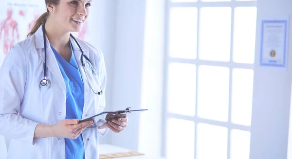 Médico sonriente con una carpeta en uniforme de pie — Foto de Stock