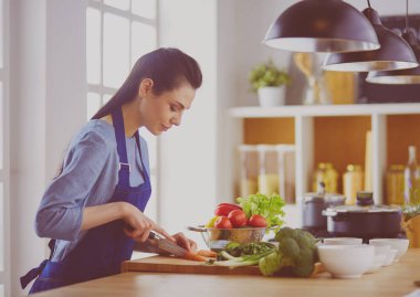 Mutfakta sebze doğrayan genç bir kadın.