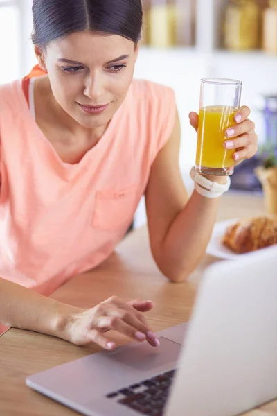 Young woman in kitchen with laptop computer looking recipes, smiling. Food blogger concept — Stock Photo, Image