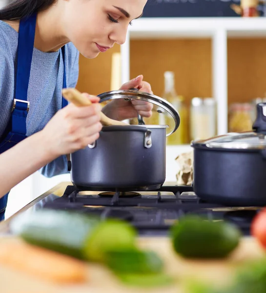 Mujer cocinera en cocina con cuchara de madera — Foto de Stock