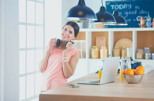 Mooie vrouw aan de telefoon met behulp van laptop thuis in de keuken — Stockfoto