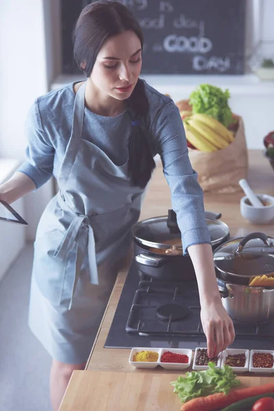 Schöne junge Frau kocht zu Hause in der Küche. — Stockfoto