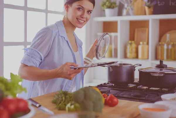 Young woman using a tablet computer to cook in her kitchen. — Stock Photo, Image