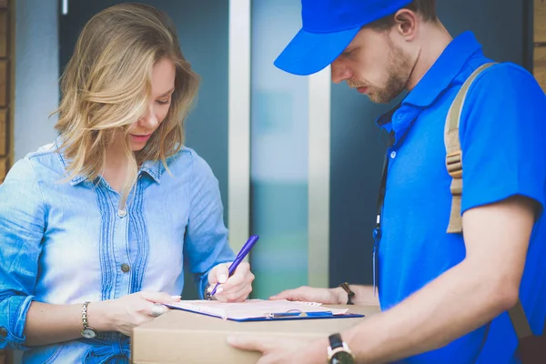 Χαμογελαστή παράδοση άνθρωπος σε μπλε στολή παράδοση δεμάτων κουτί στον παραλήπτη - έννοια της υπηρεσίας ταχυμεταφορών — Φωτογραφία Αρχείου