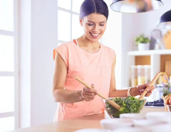 Mosolygó fiatal nő keverés friss saláta a konyhában. — Stock Fotó