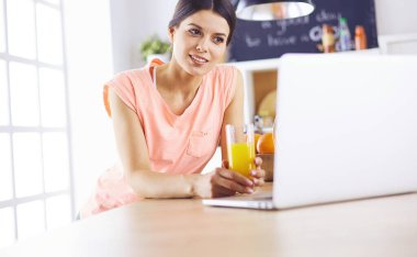 Mutfakta dizüstü bilgisayara benzeyen tariflerle gülümseyen genç bir kadın. Gıda blogcusu kavramı