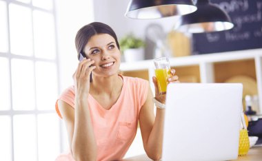 Mutfakta dizüstü bilgisayara benzeyen tariflerle gülümseyen genç bir kadın. Gıda blogcusu kavramı