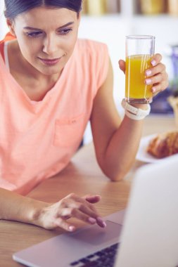 Mutfakta dizüstü bilgisayara benzeyen tariflerle gülümseyen genç bir kadın. Gıda blogcusu kavramı