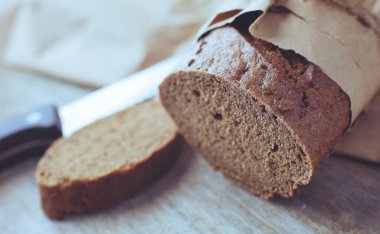 Tahta masanın üzerinde kağıda sarılı bir somun ekmek..