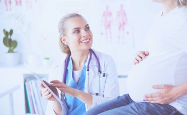 Gülümseyen kadın doktor resimlerini tablette hastanedeki hamile genç bayana gösteriyor..