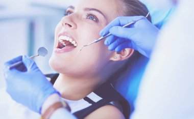 Dişçi muayenehanesinde diş muayenesi yapan ağzı açık genç bir kadın hasta..