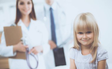 Kadın doktor ameliyatta steteskopla çocuğu muayene ediyor.