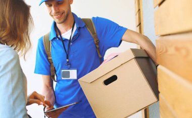 Mavi üniformalı gülümseyen kurye servis konseptine paket kutusu teslim eden teslimatçı. Mavi üniformalı gülümseyen teslimatçı.