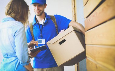 Mavi üniformalı gülümseyen kurye servis konseptine paket kutusu teslim eden teslimatçı.