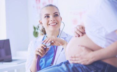 Genç bayan doktor klinikte hamile kadını muayene ediyor..