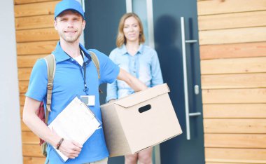 Mavi üniformalı gülümseyen kurye servis konseptine paket kutusu teslim eden teslimatçı. Mavi üniformalı gülümseyen teslimatçı.