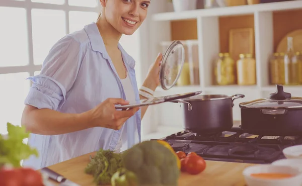 Young woman using a tablet computer to cook in her kitchen. — Stock Photo, Image