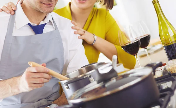 Attractive couple in love cooking and opens the wine in the kitchen while they cook dinner for a romantic evening — Stock Photo, Image