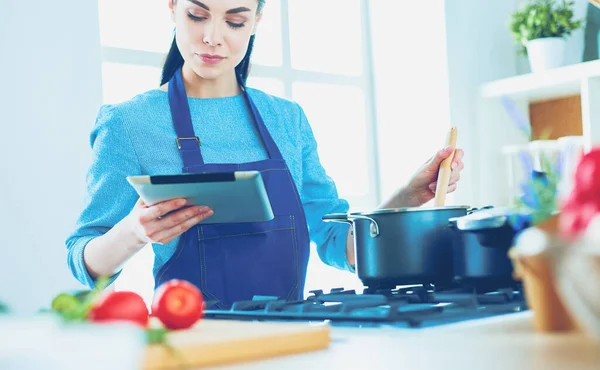 Junge Frau kocht mit Tablet-Computer in ihrer Küche — Stockfoto