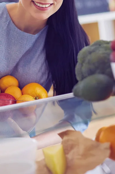 Smiling woman taking a fresh fruit out of the fridge, healthy food concept — Stock Photo, Image