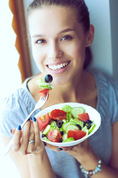 美しい女の子が健康的な食べ物を食べて窓の近くに座って — ストック写真